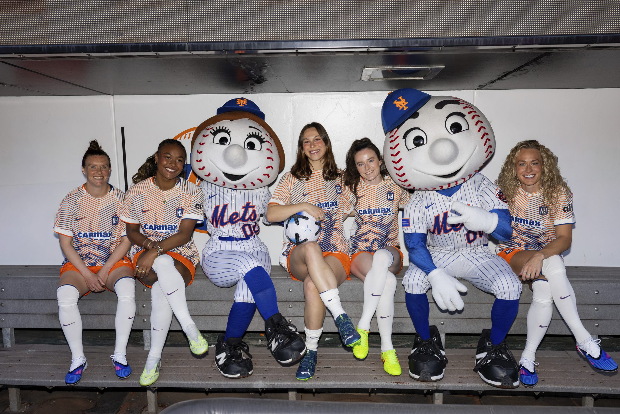 Gotham FC players pose in the Citi Field dugout with New York Mets mascots Mr. and Mrs. Met.