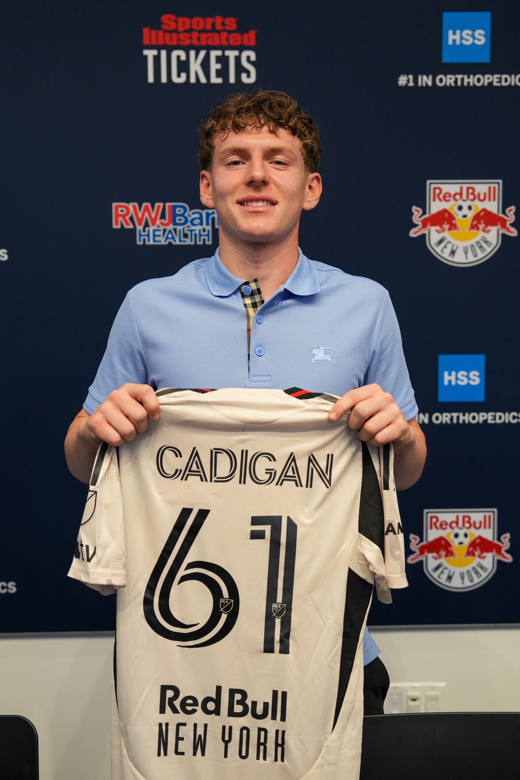 Deven Cadigan holds a No. 61 Red Bull New York jersey.