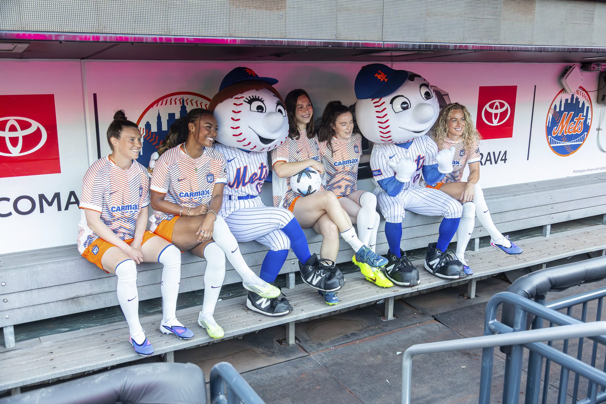 Gotham FC players pose in the Citi Field dugout with New York Mets mascots Mr. and Mrs. Met.